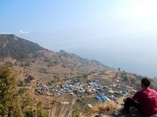 Matthias Eckert sitz an einem Abhang und blickt über das Dorf