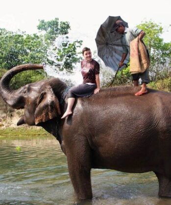 Frau wird von Elefant mit Wasser angespritzt
