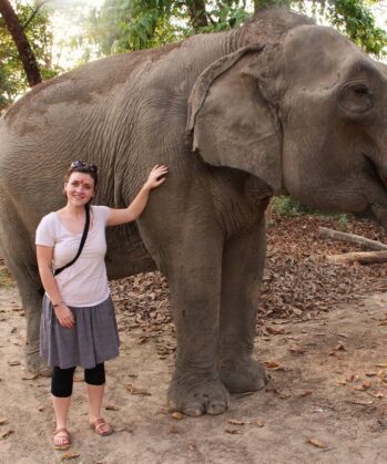 Frau streichelt trinkenden Elefant