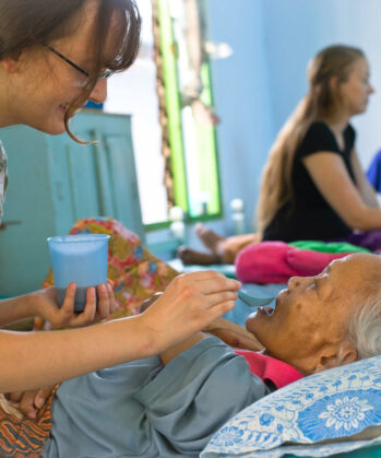 Voluntärin beim füttern einer pflegebedürftigen alten Frau