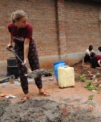 Volontärin mit Schaufel hilft in einem Bau-Workcamp in Uganda