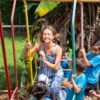 Volontärin schaukelt mit Kinder aus dem Projekt